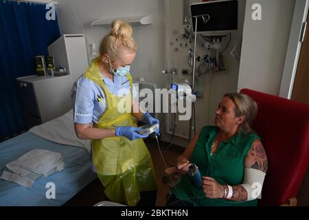 Eine Mitarbeiterin des klinischen Personals trägt persönliche Schutzausrüstung (PSA), während sie den Patienten Trudy Woodfall betreut, der sich auf der Covid Recovery Station im Royal Papworth Hospital in Cambridge vom Coronavirus erholt. Stockfoto