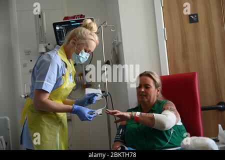 Eine Mitarbeiterin des klinischen Personals trägt persönliche Schutzausrüstung (PSA), während sie den Patienten Trudy Woodfall betreut, der sich auf der Covid Recovery Station im Royal Papworth Hospital in Cambridge vom Coronavirus erholt. Stockfoto