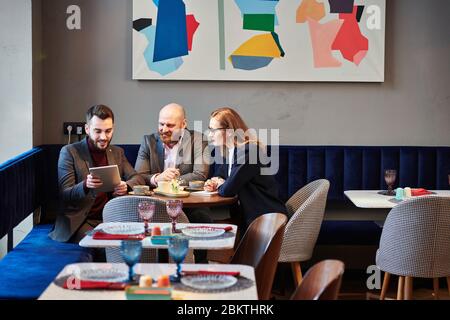 Inhalt junge Geschäftsleute Online-Präsentation auf Tablet bei Geschäftstreffen in modischem Café Stockfoto