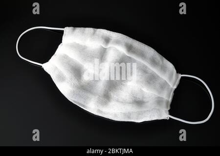 Gaze Bandagen mit elastischen Bändern über den Ohren, zu Hause gemacht, auf schwarzem Hintergrund. Atemschutz. Stockfoto