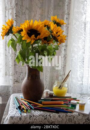 Ein Strauß von hellen Sonnenblumen in einem Tonkrug auf dem Hintergrund eines Spitzenvorhangs. Stockfoto