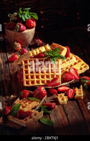 Waffeln mit Erdbeeren und Minze auf einem alten Holztisch. Stockfoto