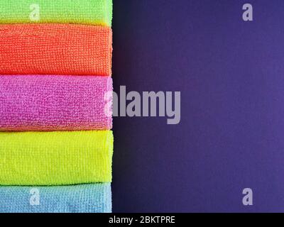 Farbige Microfaser-Handtücher auf dunklem lila Hintergrund. Nahaufnahme. terry Servietten. Stockfoto