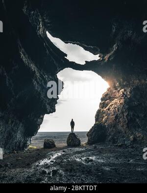 Eine Silhouette einer Person in der Höhle. Island hat sehr einzigartige Fels- und Naturformationen, die junge Abenteurer entdecken wollen Stockfoto