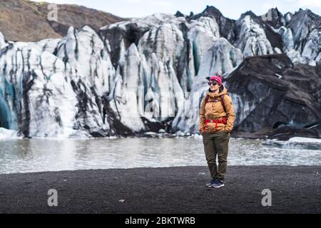 Vik, Island 28. April 2020. Eine junge Abenteuerreise, die vor dem Solheimajokull Gletscher posiert Stockfoto