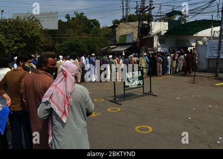 Eine große Anzahl von Menschen stehen in der Schlange, ohne soziale Distanz zu halten NADRA Büro in Shimla Hill Bereich, um ihre nationalen Ausweise zu erhalten. NADRA hat seine Büros im ganzen Land wieder eröffnet, um die Öffentlichkeit in Lahore zu erleichtern. Bewohner, die Gesichtsmasken tragen, stehen vor dem Büro der Nationalen Datenbank- und Registrierungsbehörde (NADRA) für Neuzulassungen und biometrische Verifizierungen im Rahmen des staatlichen Ehsaas-Notfallbargeldprogramms für bedürftige Familien während einer landesweiten staatlichen Lockdown als vorbeugende Maßnahme gegen die COVID-19 in einer Schlange. (Foto von Rana S. Stockfoto