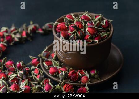 Getrocknete Teerose, Dessertrosen in einer Keramikbecher. Selektiver Fokus. Vintage-Stil. Chinesischer Rosentee. Getrocknete Rosenblüten, die für die Zubereitung von Tee verwendet werden. Stockfoto