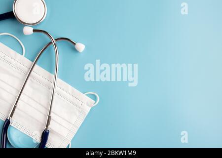 Zusammensetzung mit medizinischem Stethoskop, einmal-Gesichtsmasken auf blauem Hintergrund. Draufsicht. Freier Speicherplatz Stockfoto