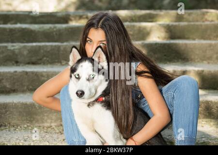 Hübsche Frau und ihr Haustier. Swag Mädchen mit ihrem Husky Hund isoliert städtischen Beton graue Treppe auf Hintergrund sitzen auf Treppen beide Blick auf Kamera. Tak Stockfoto