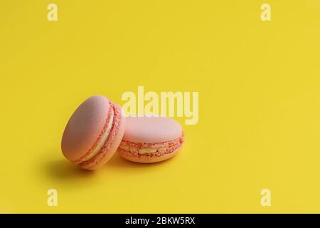Rosa Makronen. Süße Macarons auf gelbem Hintergrund mit Kopierraum Stockfoto