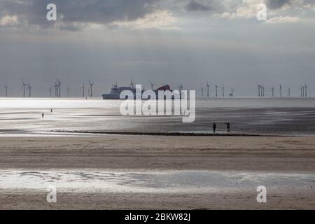 Ein Schiff, das an den Statuen von Another Place am Crosby Beach vorbeifährt, die von Sir Antony Gormley entworfen wurden Stockfoto