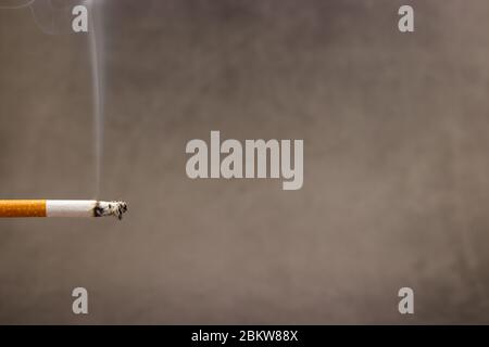 Brennende Zigarette auf dunklem Hintergrund Stockfoto