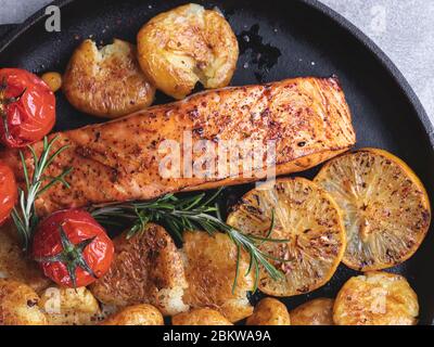 Gegrilltes Lachsfilet mit gerösteten neuen Kartoffeln, Zitrone, Tomaten Stockfoto