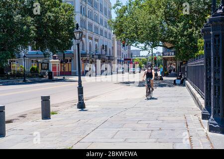 Fahrradfahrer mit Gesichtsmaske, der während der Corona-Virus-Pandemie auf dem Bürgersteig in der Decatur Street im French Quarter unterwegs ist Stockfoto