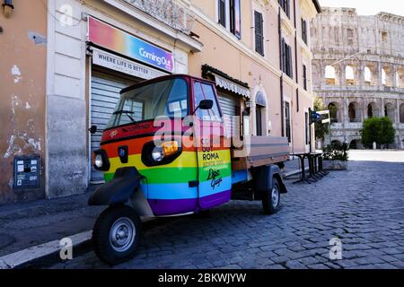 Schwulenbar geschlossen während Coronavirus, Covid 19 Lockdown. Kolosseum im Hintergrund. (Rom zur Zeit von Covid 19). Rainbow Piaggio Ape in der verlassenen Rom Homosexuell Straße geparkt. Italien, Europa, EU. Stockfoto