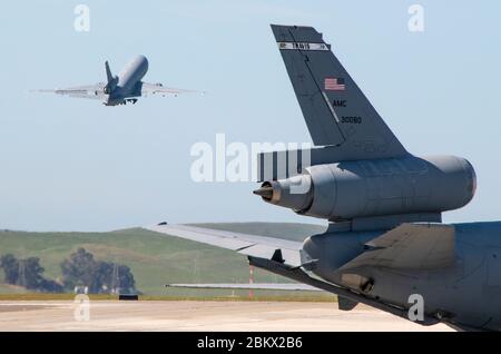 Ein US Air Force KC-10 Extender wird auf der Fluglinie geparkt, während ein anderer die Landebahn am 22. April 2020 auf der Travis Air Force Base, Kalifornien, verlässt. Obwohl die KC-10 die primäre Mission ist Luftbetankung, ist es auch in der Lage, bis zu 75 Personen und fast 170,000 Pfund Fracht zu transportieren. Das Flugzeug ist seit über 20 Jahren Teil der Mission von Travis. (USA Air Force Foto von Heide Couch) Stockfoto