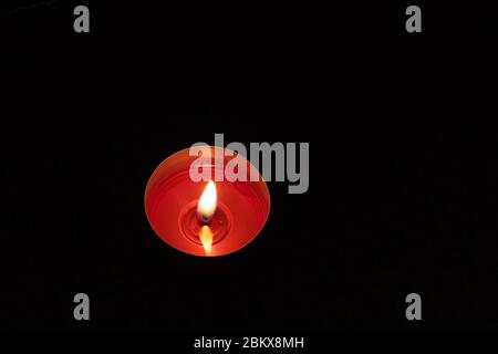 Einzelne Kerze aus nächster Nähe Hintergrund. Brennende rote Kerze auf schwarzem Hintergrund. Stockfoto