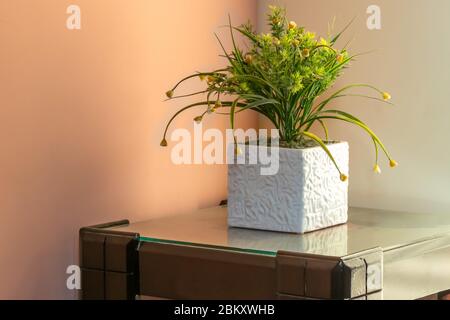 Künstlicher Blumentopf, der auf dem Tisch im Haus liegt. Stockfoto