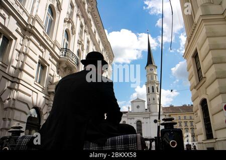 Blick hinter den Taxifahrer einer traditionellen Fiakerkette in Richtung romanische Michaelskirche in der Hofburg, Wien, Österreich. Stockfoto