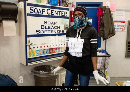 Brooklyn, NY - 6. April 2020, ein Diener an einem Waschsalon in Brooklyns Midwood-Viertel, und geschützt mit einer Gesichtsmaske und Latexhandschuhen, trägt eine Stockfoto