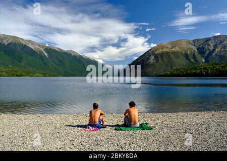 Zwei junge Männer sonnen sich am Ufer des Lake Rotoiti, Nelson Lakes National Park. Stockfoto