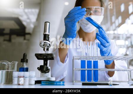 Wissenschaftler, die im Labor im weißen Labormantel recherchieren, Handschuhe analysieren, Reagenzgläser Probe betrachten, Biotechnologiekonzept. Stockfoto