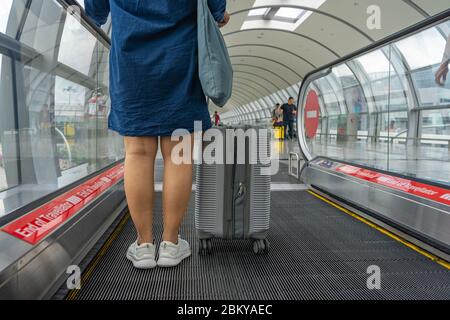 Nahaufnahme eines Fotos der Beine des Reisenden, die auf einem beweglichen Gang stehen Stockfoto