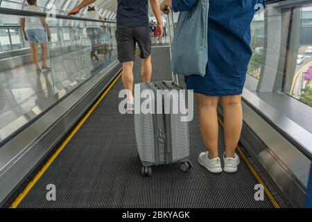 Rückansicht der Reisenden, die auf einem beweglichen Gang am Flughafen stehen Stockfoto