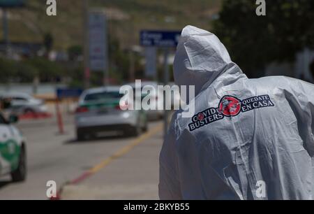 Tijuana, Mexiko. Mai 2020. Ein Mitglied der Gruppe 'Covid Busters' mit dem Logo auf dem Schutzanzug führt Desinfektionsmaßnahmen gegen die Verbreitung von Covid-19 durch. Die Gruppe hat den Namen "Ghostbusters" aus den US-Filmen übernommen und plant, Orte in der an die USA angrenzenden Stadt zu desinfizieren, wo sich viele Menschen versammeln. Die Männer nehmen kein Geld für diese Arbeit. Es sind Bürger, Freunde und Familienväter, die diesen Dienst aus Liebe und Fürsorge für ihre Stadt tun, wie sie auf Facebook schreiben. Quelle: Omar Martínez/dpa/Alamy Live News Stockfoto