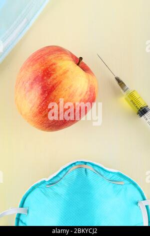Chemische Zusatzstoffe in Lebensmitteln oder genetisch veränderte Frucht Konzept. Roter Apfel mit Spritzen von Chemikalien. Isoliert auf rotem Hintergrund. Stockfoto
