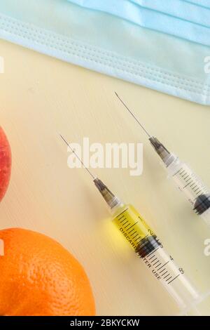 Chemische Zusatzstoffe in Lebensmitteln oder genetisch veränderte Frucht Konzept. Roter Apfel mit Spritzen von Chemikalien. Isoliert auf rotem Hintergrund. Stockfoto