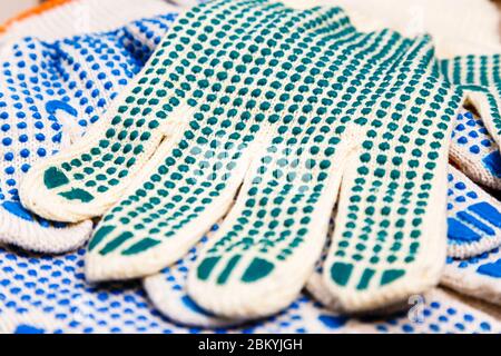 Dünne Arbeitshandschuhe mit grünen Noppen. Hintergrund der persönlichen Schutzausrüstung. Arbeitsschutzkonzept. Stockfoto