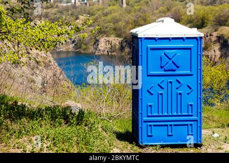 Blaue Kabine von Bio-WC in einem Bergpark auf einem Fluss Hintergrund bei sonnigen Sommertag. Stockfoto