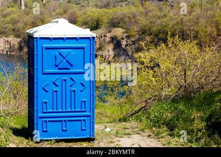 Blaue Kabine von Bio-WC in einem Bergpark an sonnigen Sommertag. Stockfoto