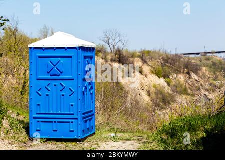 Blaue Kabine von Bio-WC in einem Bergpark an sonnigen Sommertag. Stockfoto