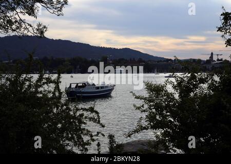 Sonnenuntergang Flusslandschaft mit geparktem Boot und einigen Büschen fotografiert Zürich Schweiz, Juli 2018. Wunderschöner, farbenfroher Sonnenuntergang hinter den Alpen. Stockfoto