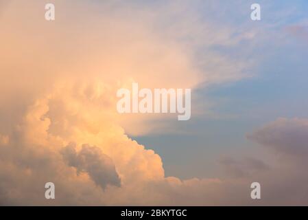 Flauschige Wolken glühen rosa bei Sonnenuntergang vor blauem Himmel Hintergrund. Stockfoto