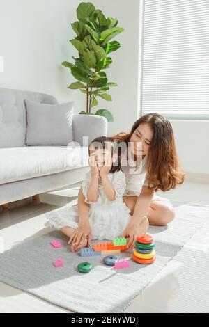 Mutter und Tochter spielen ein Spielzeug und haben Spaß im Wohnzimmer Stockfoto