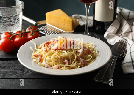 Komposition mit Teller mit schmackhafter Pasta und Wein auf Holzhintergrund Stockfoto