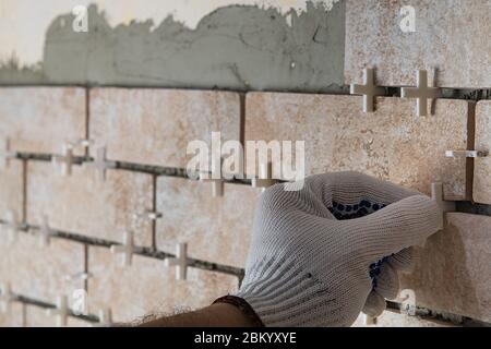 Keramikfliesen liegen. Installation neuer U-Bahn Fliesen in der Küche zurück Splash während der Renovierung. Platzieren oder Ausnehmen von Bodenabstandshaltern mit den Händen. Stockfoto