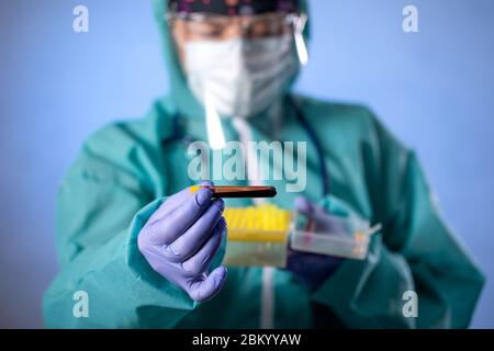 Arbeiter halten 2019-nCoV Coronavirus Teströhrchen , COVID-19, Coronavirus Epidemie Krankheit mit Arzt oder Labortechniker Wissenschaftler in PPE Personal Protec Stockfoto