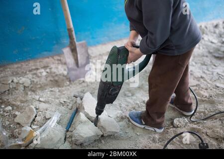 Kleiner Junge hämmert mit einem Handhammer auf den Boden Stockfoto