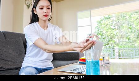 Asiatische Business Frau arbeitet von zu Hause aus und sie reinigt ihre Hände mit Desinfektionsmittel Gel für schützende Coronavirus.Sie wird zu Hause während Quarantäne Stockfoto