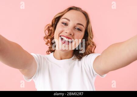 Foto von einer netten positiven optimistischen jungen hübschen Frau posiert isoliert über rosa Wand Hintergrund nehmen Sie ein Selfie mit der Kamera. Stockfoto