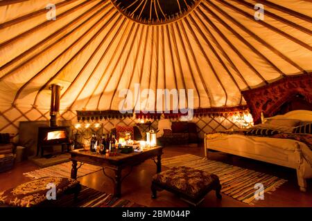 Interieur der gemütlichen Jurte in der Nacht mit Kerzen und Holzofen auf Glamping Campingplatz Wowo's in Sussex, Großbritannien Stockfoto