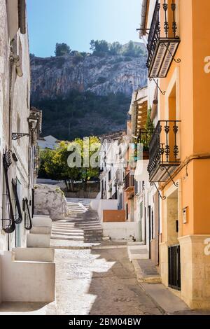 Eine schmale Straße in der Altstadt von Xativa in der Provinz Valencia mit Balkonen mit Blick auf die Stufen, die zu den Bergen führen. Stockfoto