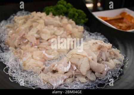 Große Portion rohen Seegroßlachs wird auf einem schwarzen Teller serviert. Stockfoto