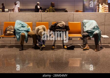 Reisende schlafen auf Sitzen im internationalen Flughafen Hamad in Doha, Katar. Stockfoto