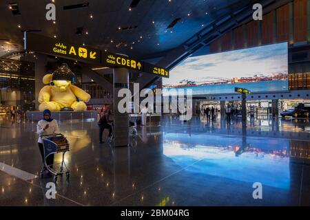 Eine Frau mit Hijab überprüft ihr Smartphone im Terminal am internationalen Flughafen Hamad in Doha, Katar. Stockfoto
