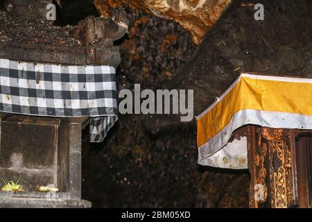 Altäre im Pura Goa Lawah oder bat Cave Temple. Balinesischer Hindu-Tempel, Klungkung, Bali, Indonesien. Einige Fledermäuse fliegen unter einem Felsüberhang. Kolonie von Fledermäusen ha Stockfoto